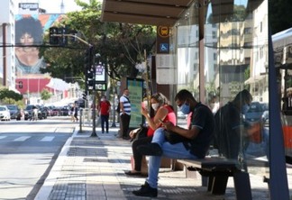 Usuários de transporte público usam máscaras de proteção contra covid-19 em ponto de ônibus na rua da Consolação