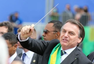O presidente Jair Bolsonaro,quebra o protocolo desce do palanque, pega uma batuta e faz gestos de maestro ao se aproximar a pé, das arquibancadas onde fica o público na Esplanada dos Ministérios