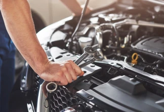 Picture showing muscular car service worker repairing vehicle.