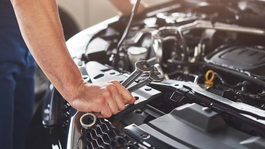 Picture showing muscular car service worker repairing vehicle.