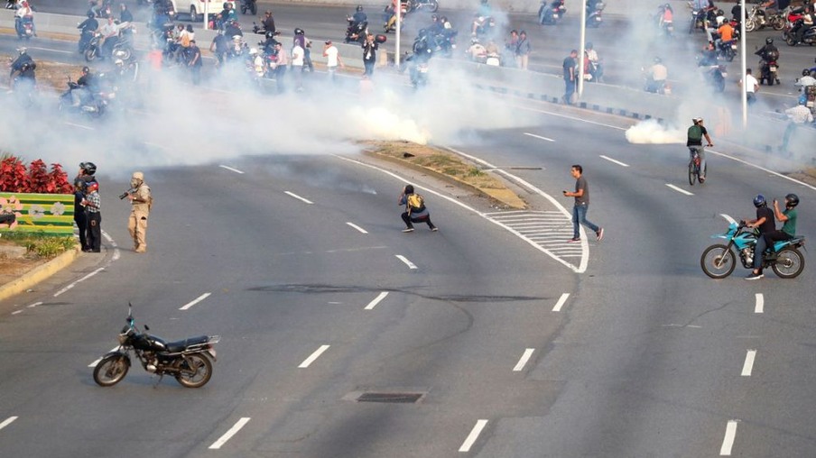 Partidários da oposição venezuelana reagem ao gás lacrimogêneo perto da Base Aérea "La Carlota", em Caracas, Venezuela. / Reuters/Carlos Garcia Rawlins/Direitos Reservados
