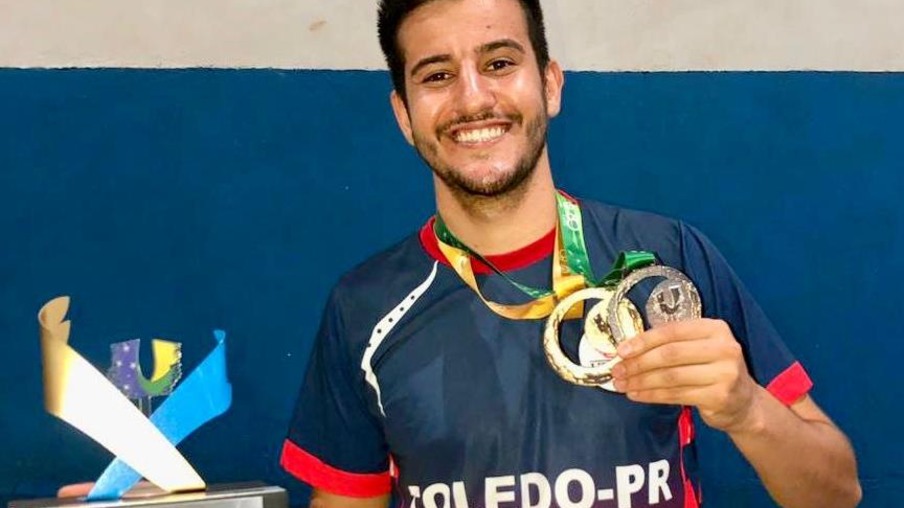 Atleta Alisson exibe medalhas e troféu de tetracampeão na modalidade de badminton 