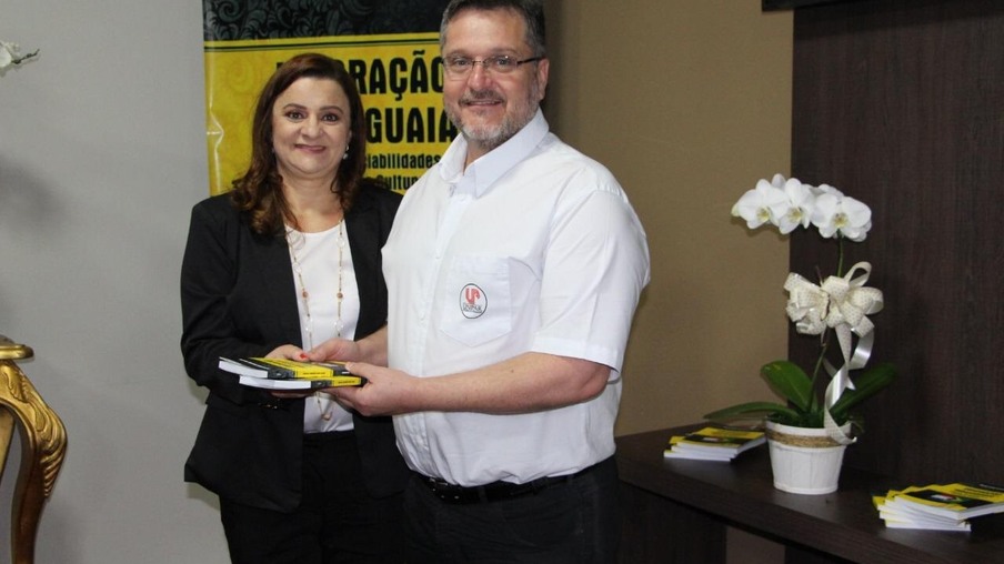 Professora Marta Izabel entrega exemplares ao diretor da Unipar, professor Sérgio Ricardo Ferrazoli