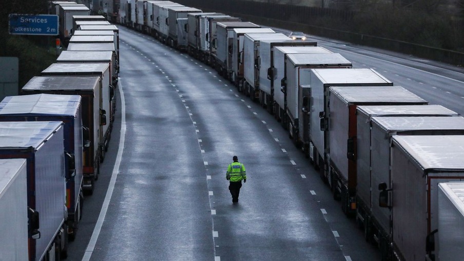 A man walks past lorries parked on the M20 motorway, as EU countries impose a travel ban from the UK following the coronavirus disease (COVID-19) outbreak, near Ashford, Britain, December 22, 2020. REUTERS/Simon Dawson
