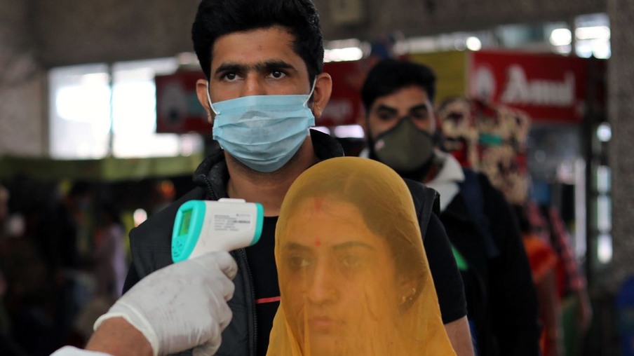 Um trabalhador de saúde em equipamentos de proteção individual (EPI) verifica a temperatura dos passageiros em meio à propagação da doença coronavírus (COVID-19), em uma estação ferroviária em Mumbai, Índia, 19 de dezembro de 2020. REUTERS / Francis Mascarenhas