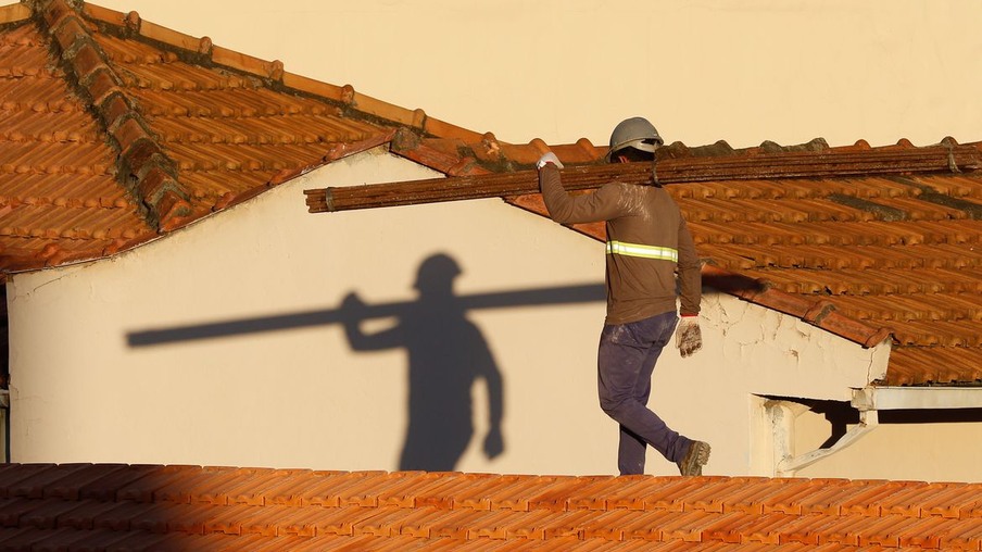 Trabalhadores da construção civil, operários reformam telhado de imóvel em obras no Centro do Rio.