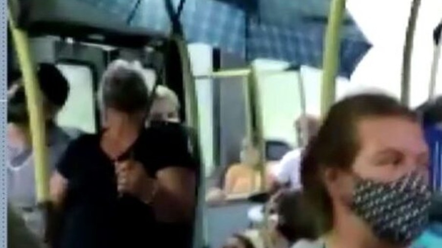 Mulher usa guarda-chuva dentro de ônibus para não se molhar com chuva no veículo, em linha do litoral do Paraná