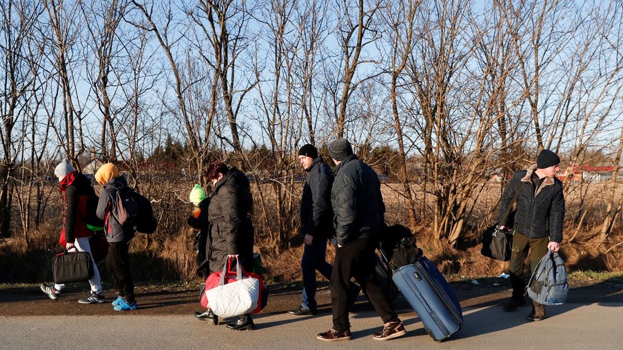 People carry their luggage as they flee from Ukraine at the Hungarian-Ukrainian border after Russian President Vladimir Putin authorized a military operation, in Tiszabecs, Hungary, February 24, 2022. REUTERS/Bernadett Szabo